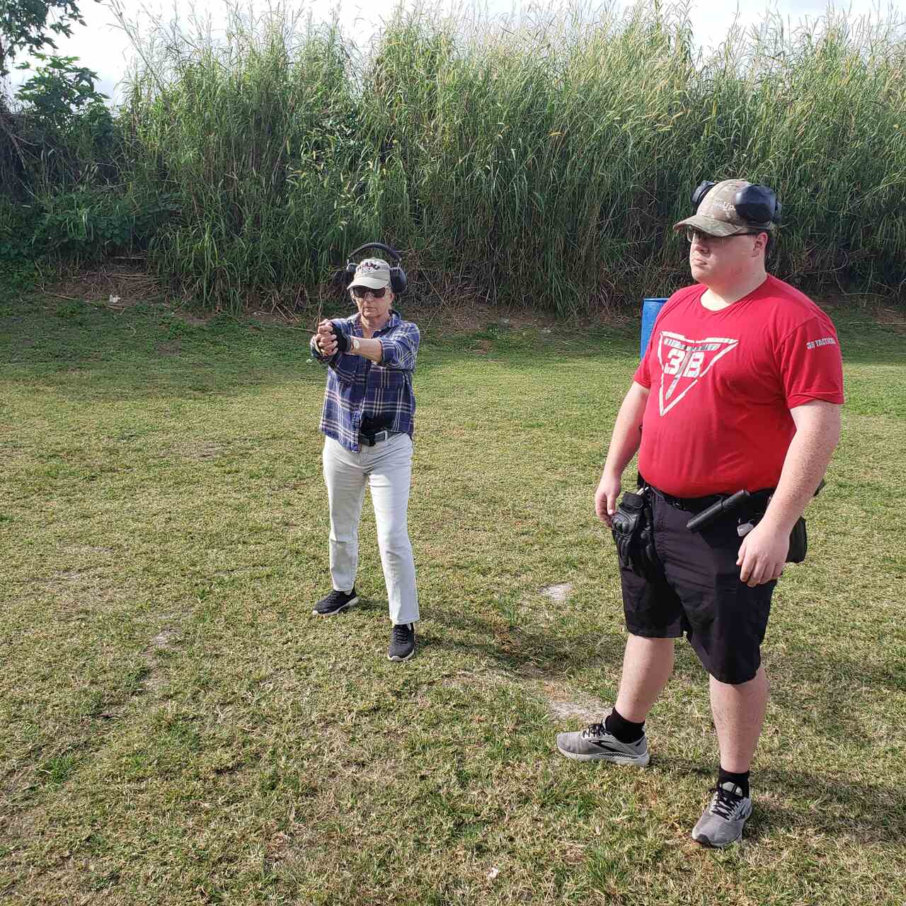 Female trainee aiming at a target with a male trainee observing at the shooting range at 3B Tactical in Miami, FL