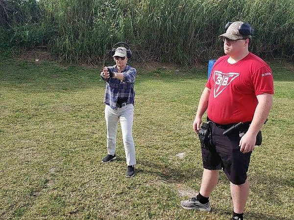 Female trainee aiming at a target with a male trainee observing at the shooting range at 3B Tactical in Miami, FL