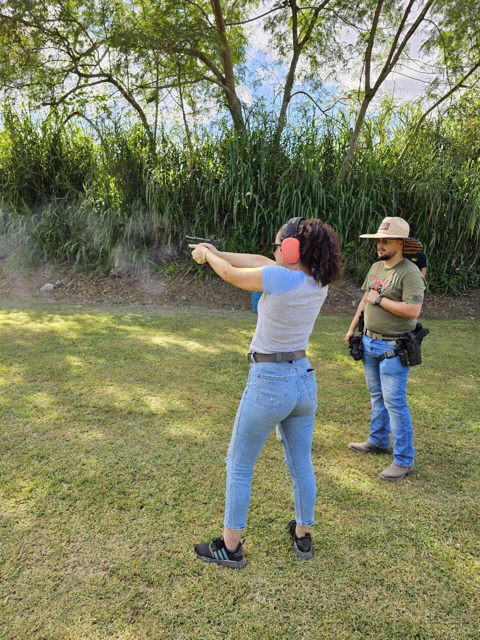 Female trainee aiming at a target while the instructor observes during a training session at 3B Tactical in Miami, FL