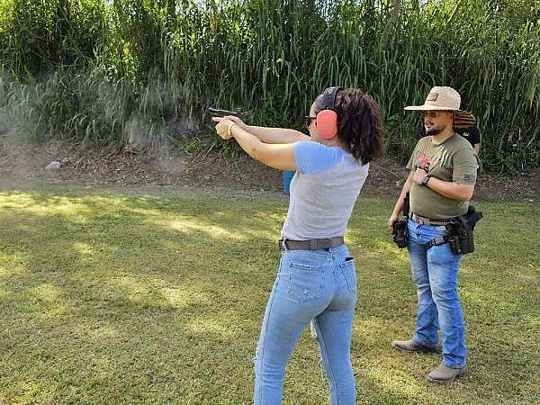 Female trainee aiming at a target while the instructor observes during a training session at 3B Tactical in Miami, FL